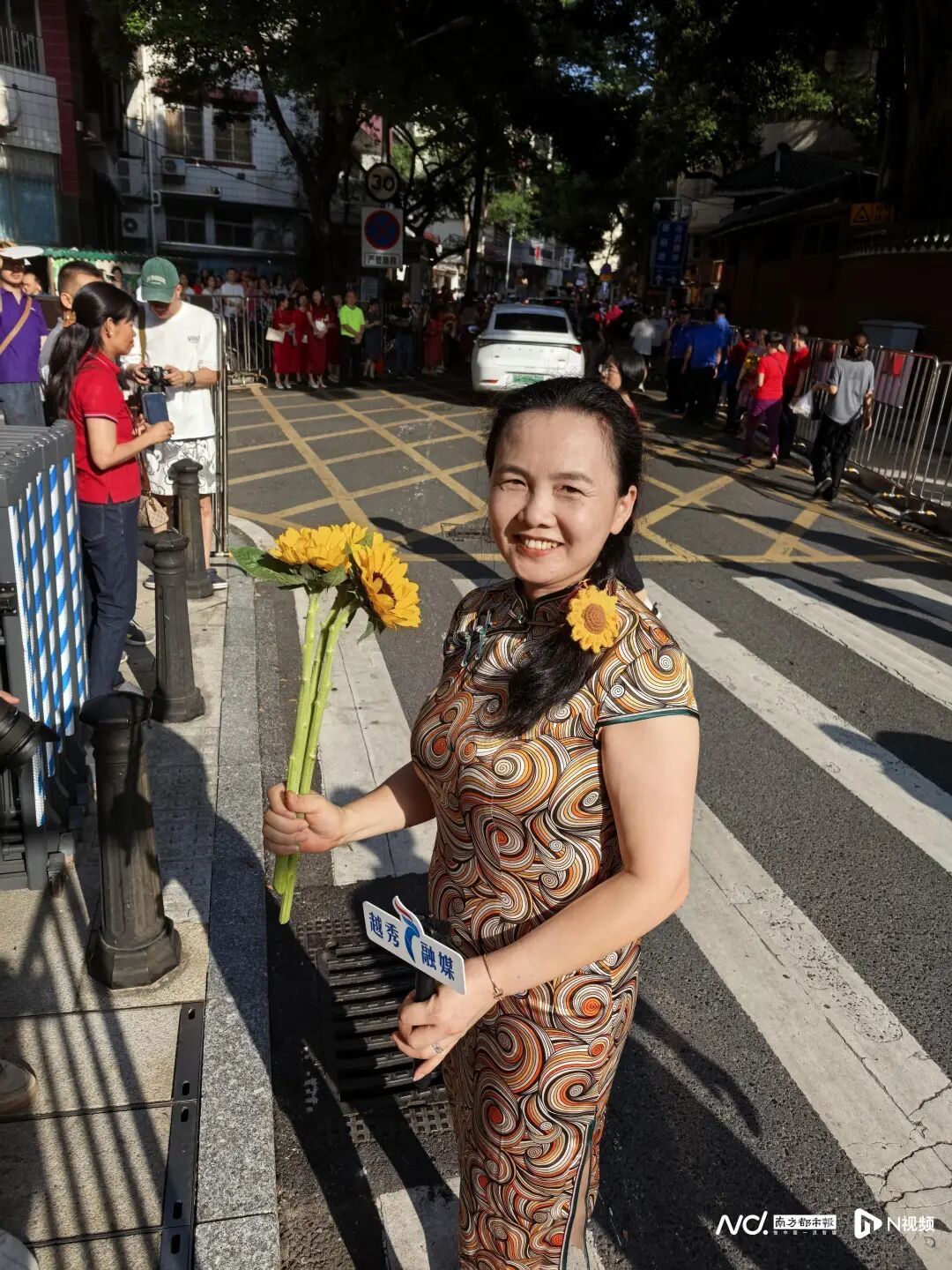 七中考点外，家长身穿旗袍、带上向日葵送考。