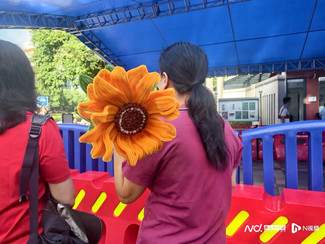 华附考点外，家长们带上向日葵来送考。