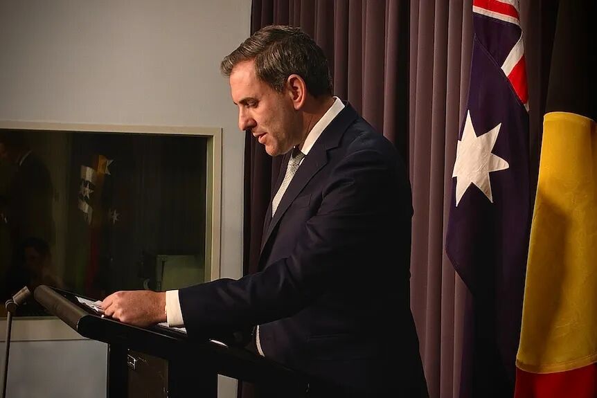 Jim Chalmers in a suit standing at a lectern