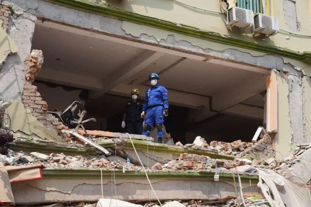 当地时间2025年3月30日,中国蓝天救援队队员站在缅甸曼德勒Sky Villa倒塌的住宅楼里,等待进一步救援方案。由于30日下午1时38分发生了余震,增加了救援的危险程度。图/南方周末记者 翁洹