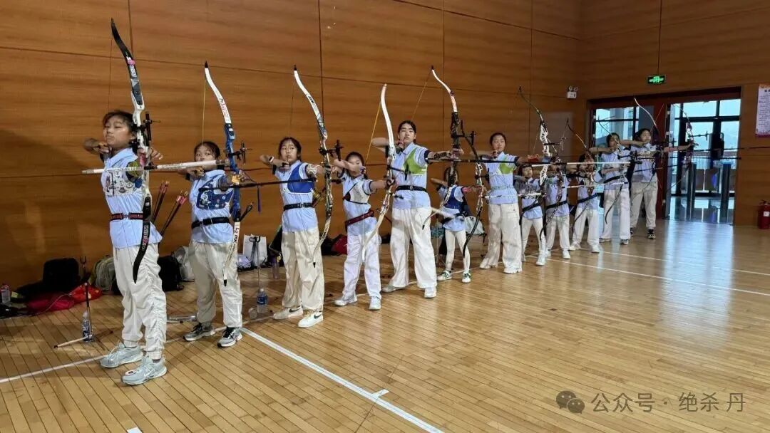 室内场馆里一排孩子同时拉满弓