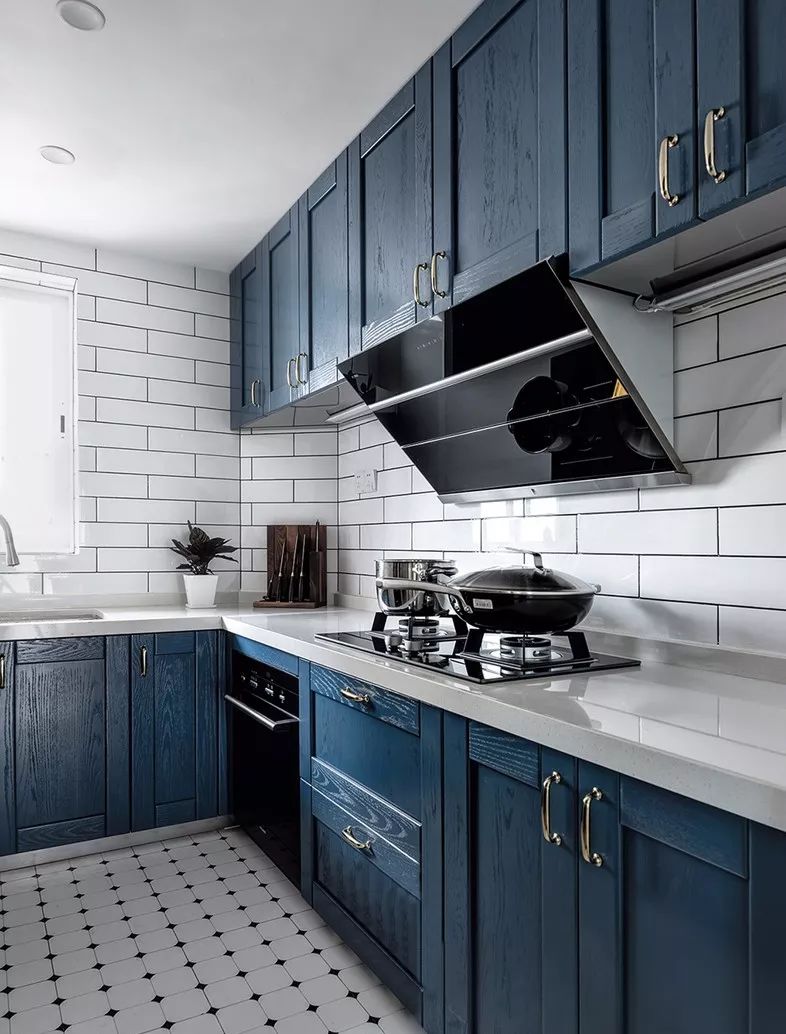 厨房蓝色实木柜门配合不锈钢柜体坚实耐用,花色瓷砖地板的搭配俏皮