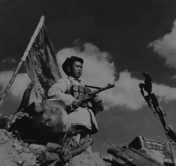 志愿军第15军官兵将布满381个弹孔的战旗插在上甘岭主峰阵地是的