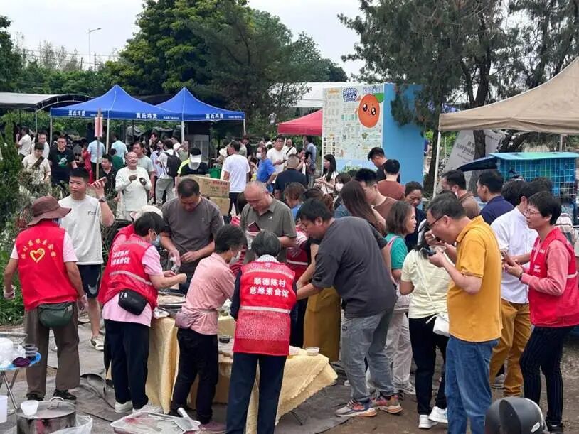 图为莫氏鸡煲店附近，义工们为游客免费赠送甜品小吃。兰航宇 摄