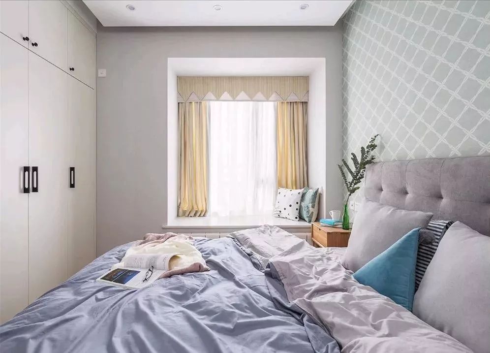 空间小，所以由硬装到软装都采用浅色系，床头铺贴绿色格子的壁纸，营造出一个小清新的卧室。