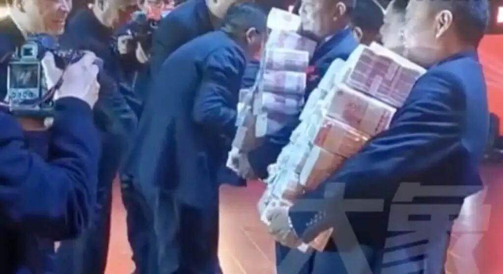 Company employees pictured carrying stacks of cash to be distributed. Photo: Elephant News