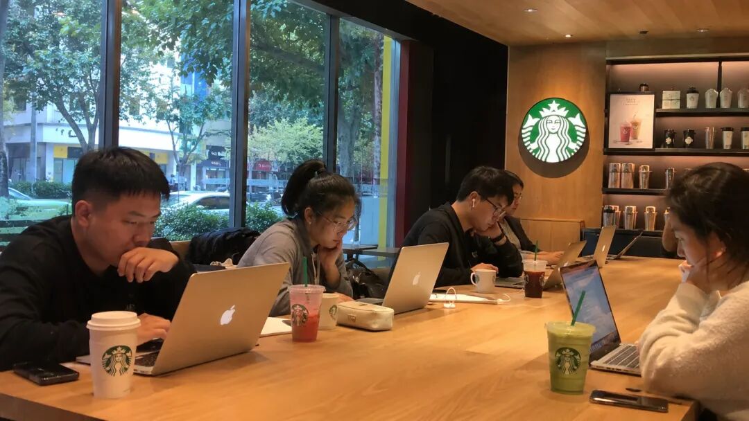 星巴克长桌前一群人都在用电脑工作