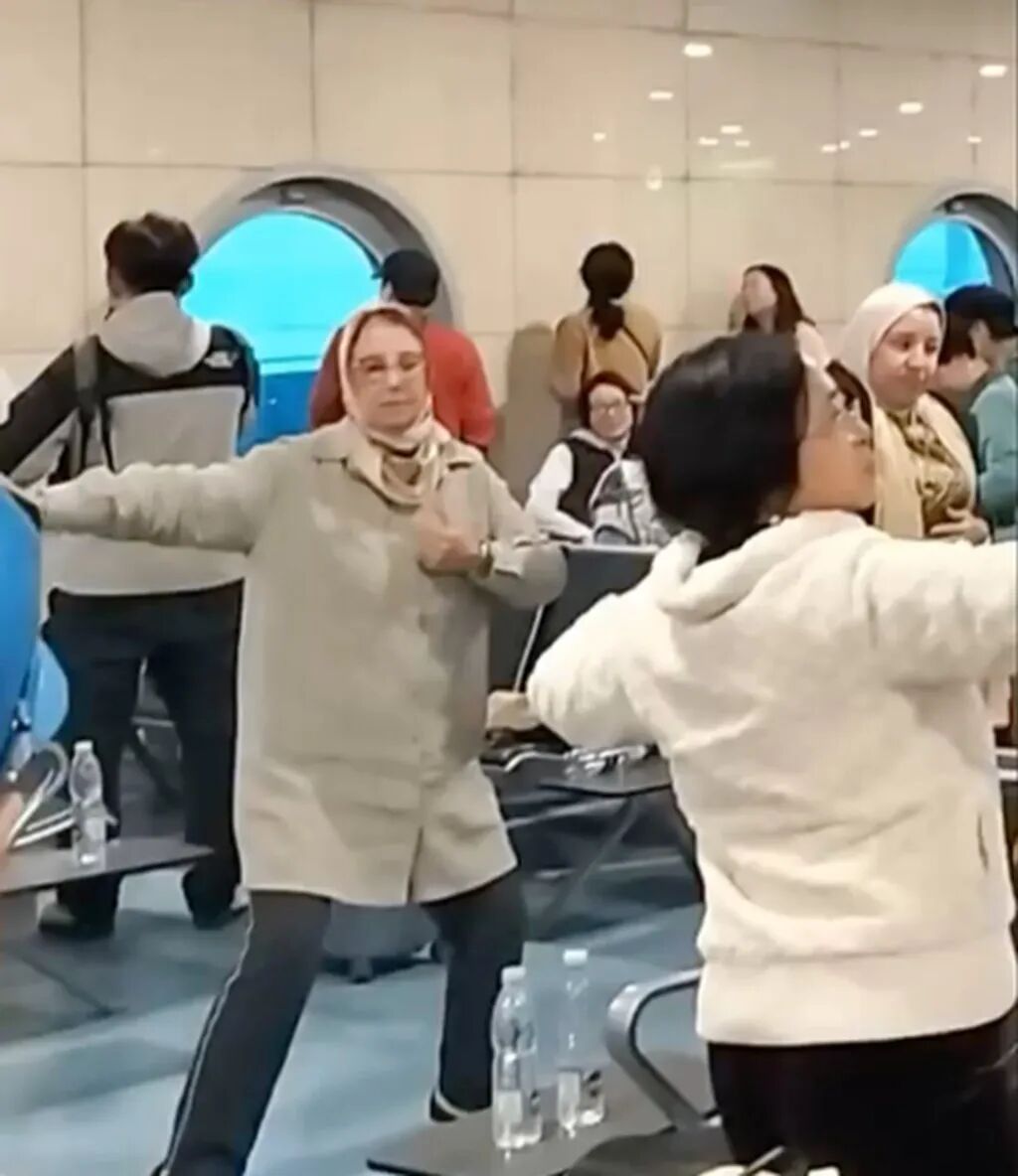 Chinese and foreign passengers spread their arms as they dance inside Cairo Airport. Photo: 8world