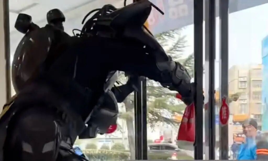 A curious passer-by, far-right, looks on as Zhou leaves the shop wearing his exoskeleton. Photo: QQ.com