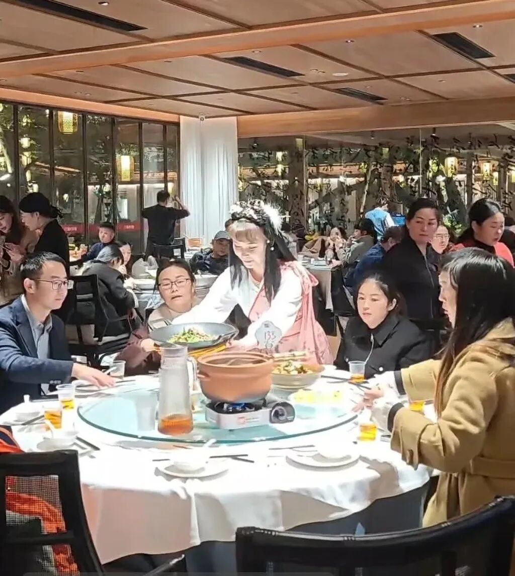 An in-character waitress, portraying Huang Rong, smiles as she serves up some dishes for customers. Photo: Douyin