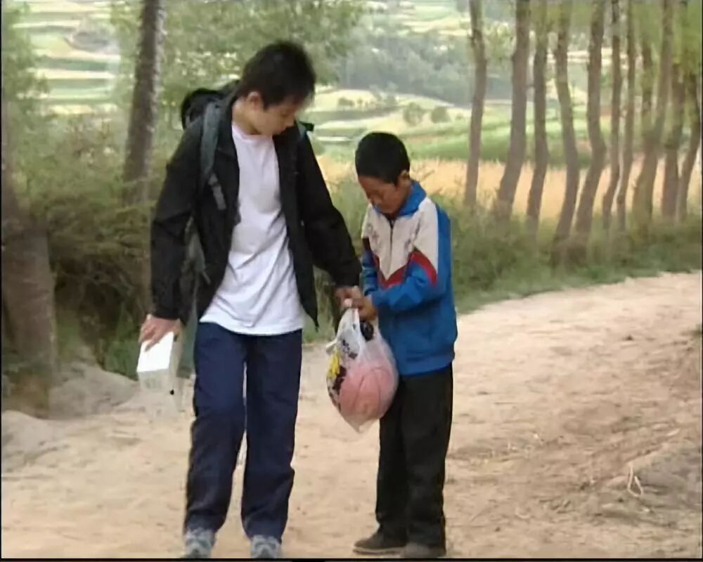 在村口的小土路上,两位主人公相见,高占喜用塑料袋拎着新爸妈送给他的