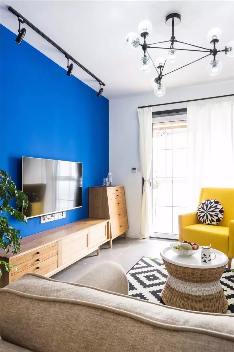 电视背景墙采用了高纯度的蓝色,单人沙发用了明黄色,让客厅空间