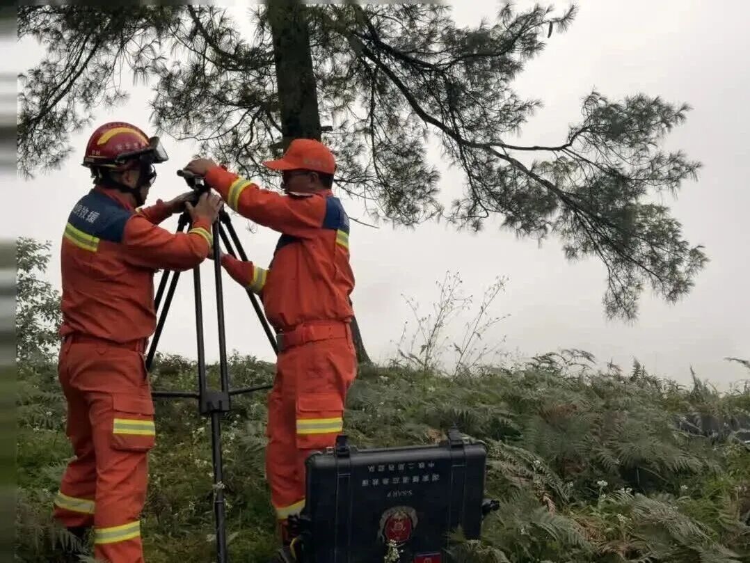 救援人员在山坡架设三脚架监测设备
