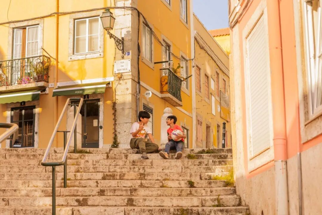 Children sit on a staircase in Lisbon's colourful streets