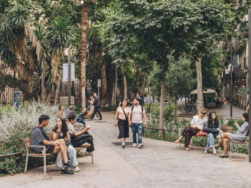 People sitting a walking through a park in Barcelona