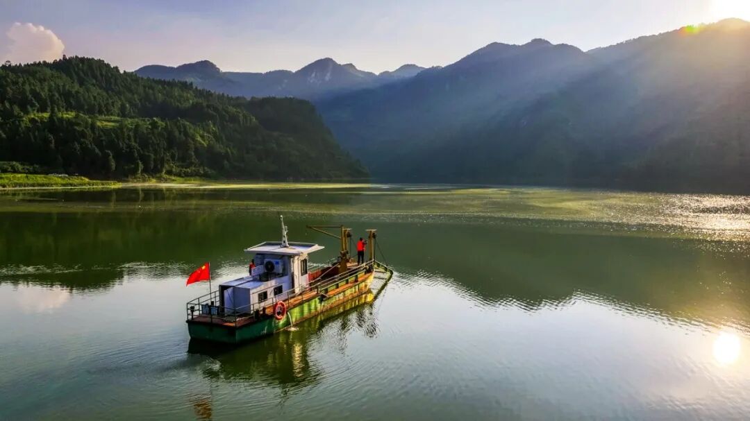 太阳逐渐西斜，波光粼粼，水面上，卢锡永跳上铁皮船，把塑料瓶里的柴油加入油箱，妻子冉戌英解开岸边捆着的绳索，跃上船。黎敬程摄.jpg