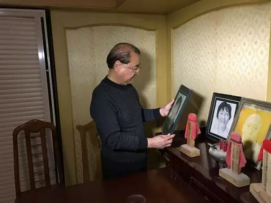 ▎王伯官在端详妻子遗像.