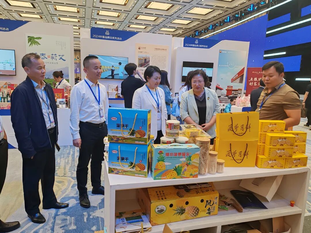 中共徐闻县委书记罗红霞和中国国家品牌网副总裁霍菲菲参观徐闻菠萝展台。