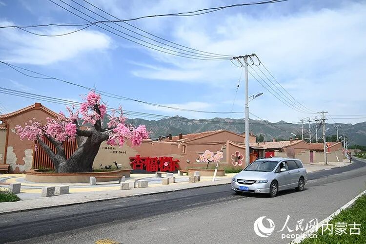 东乌素图村口，柏油路通畅，“杏福树下”标识醒目。人民网记者 刘艺琳摄