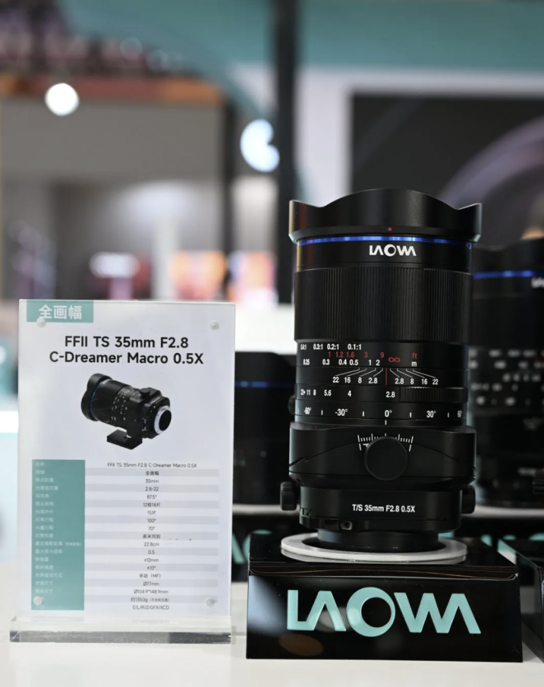 A Laowa FFII TS 35mm F2.8 macro lens is displayed next to its product information card on a stand.