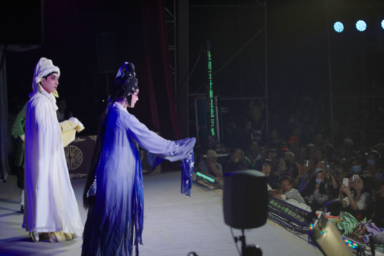 台下村民用手机记录剧团演出。 