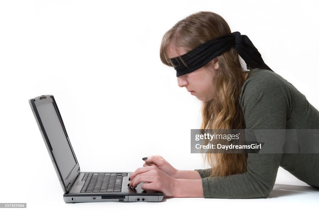 A stock image of a woman using an old computer wearing a blindfold