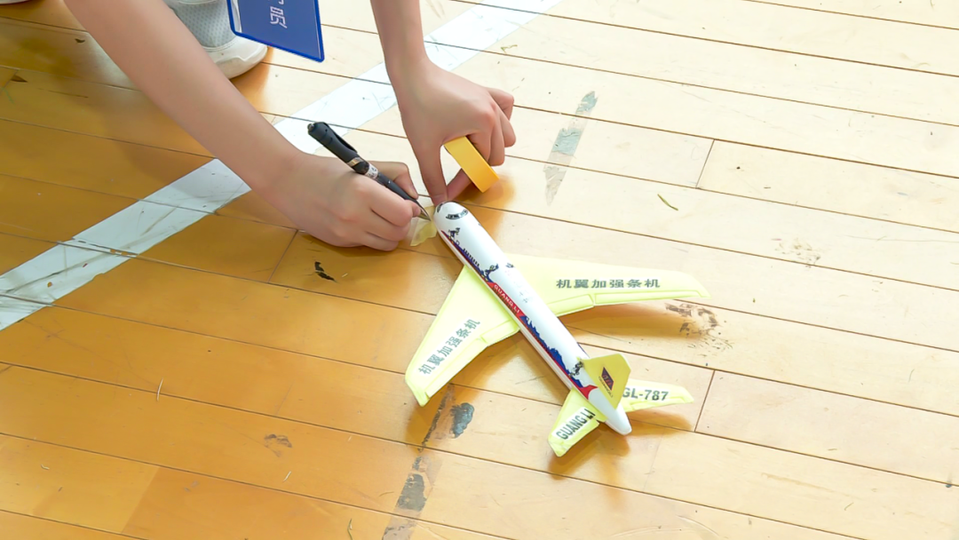 当天,在手掷滑翔机直线距离比赛中,小选手们将自己精心制作的模型飞机