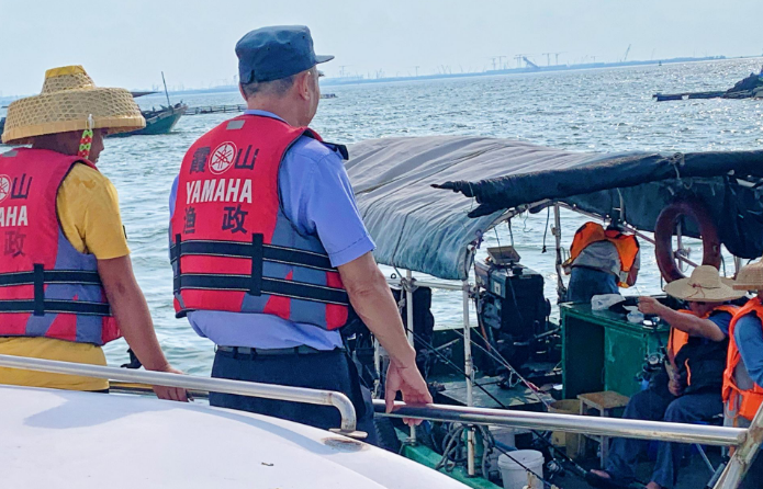 湛江霞山区海洋综合执法大队在渔港巡查，要求渔船落实防台风要求。