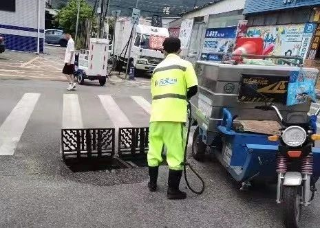 江门市外海街道环卫公司工作人员清理道路沙井盖附近的杂物垃圾。