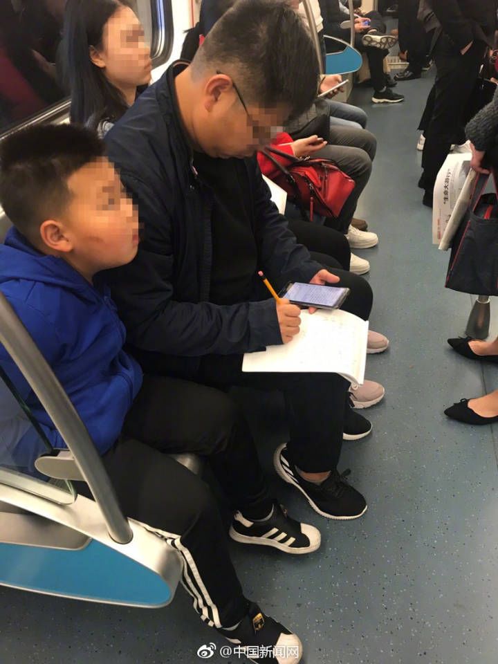 亲爸！早高峰地铁上专心致志检查儿子作业……