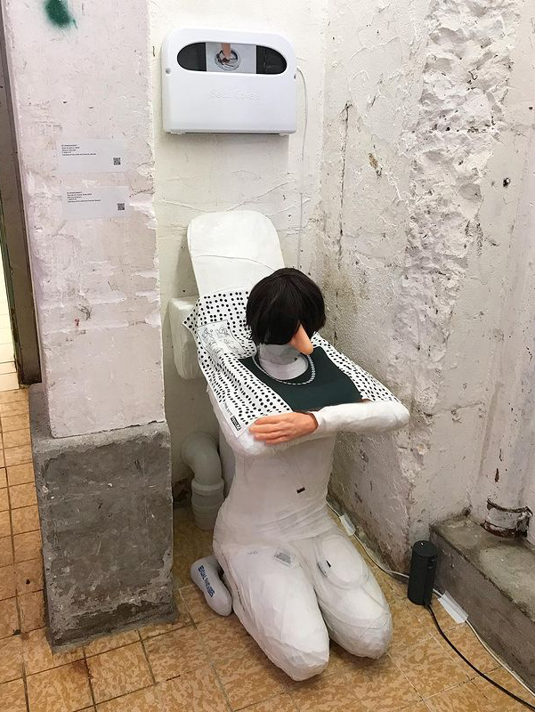 厕所",雕塑的人形蹲下形成底座,手臂拱起形成盖子,她的陶瓷马桶还会说