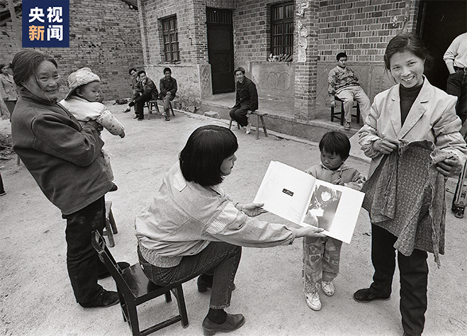 苏明娟的妈妈（右一）拿出女儿的上衣与“大眼睛”照对比（解海龙摄）