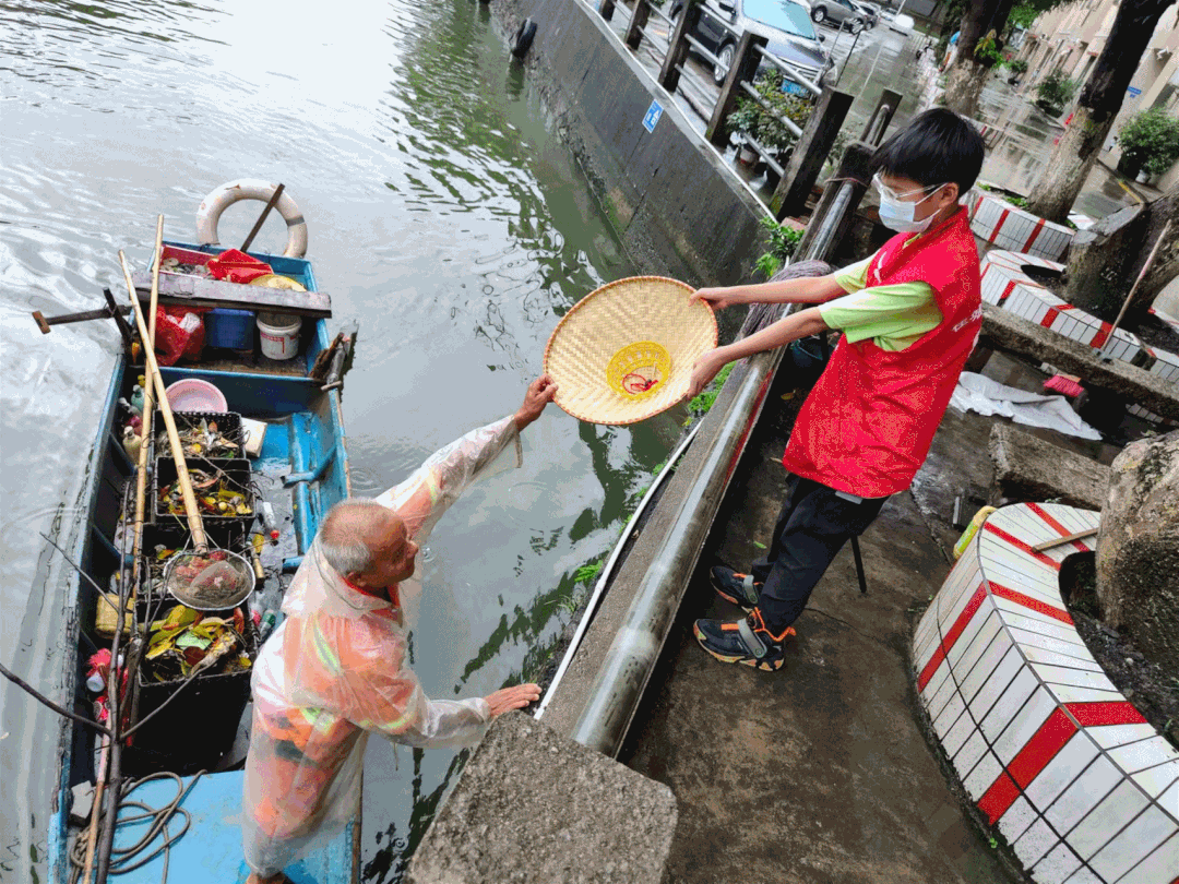 志愿者们为在高温作业下的环卫工人派发草帽。