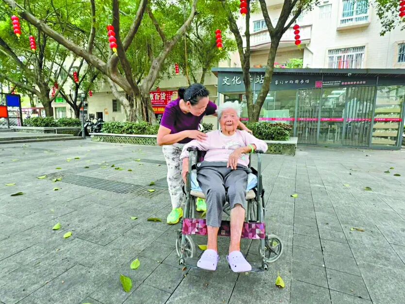 保姆张兰推着黄瑞云在公园里散步。