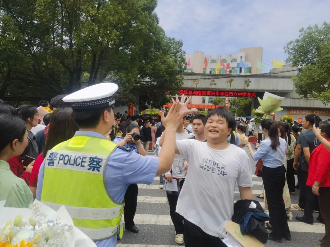 "资兴市立中学考点门口交警蜀黍与入场考生热情地击掌鼓劲用笑容为
