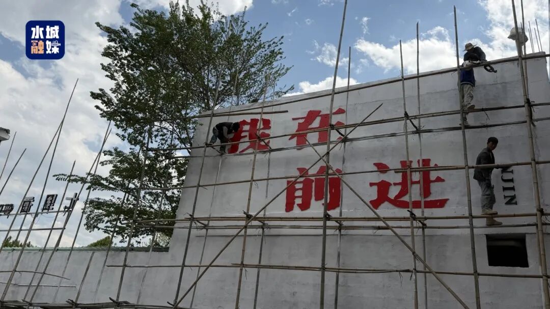 工人正在脚手架上安装“我在前进”主题标识大字。周瑞平摄.jpg