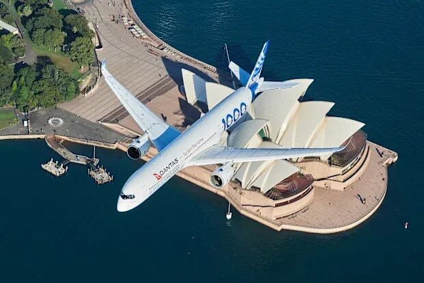 A Qantas plane flying over the top of the Sydney Opera House in Sydney, Australia