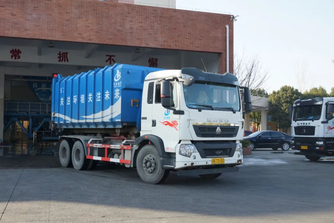 拉臂式垃圾运输车将移动式压缩箱装车后运往扬州专业垃圾处理企业进行