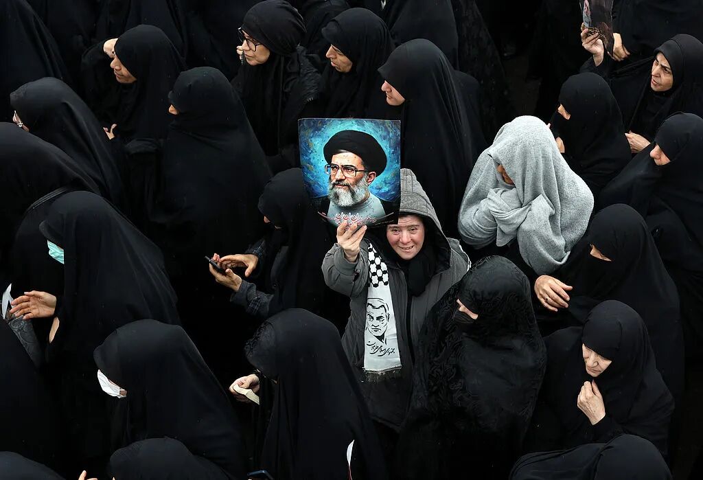 当地时间2026年3月20日，伊朗德黑兰一场葬礼上，一名伊朗女性手持已故伊朗最高领袖哈梅内伊的画像。图/视觉中国