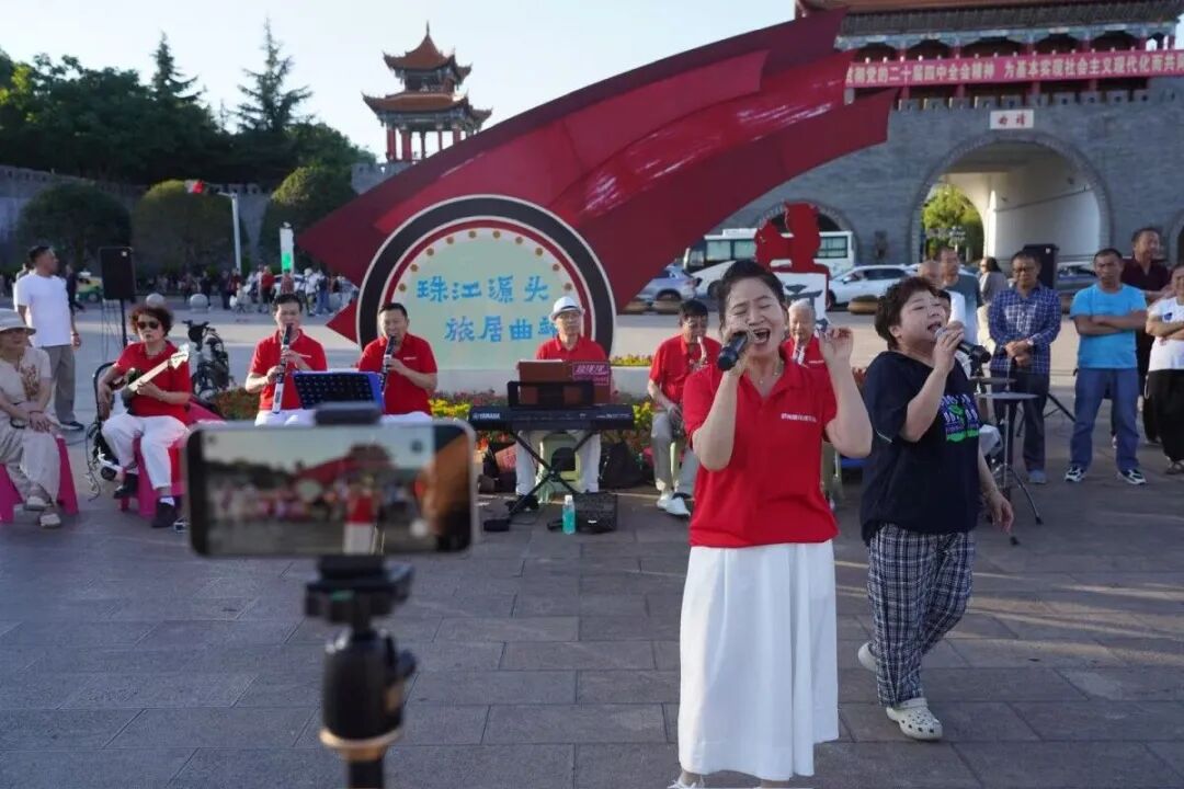 有老人支起一台手机，在曲靖南城门广场上录制唱歌视频。