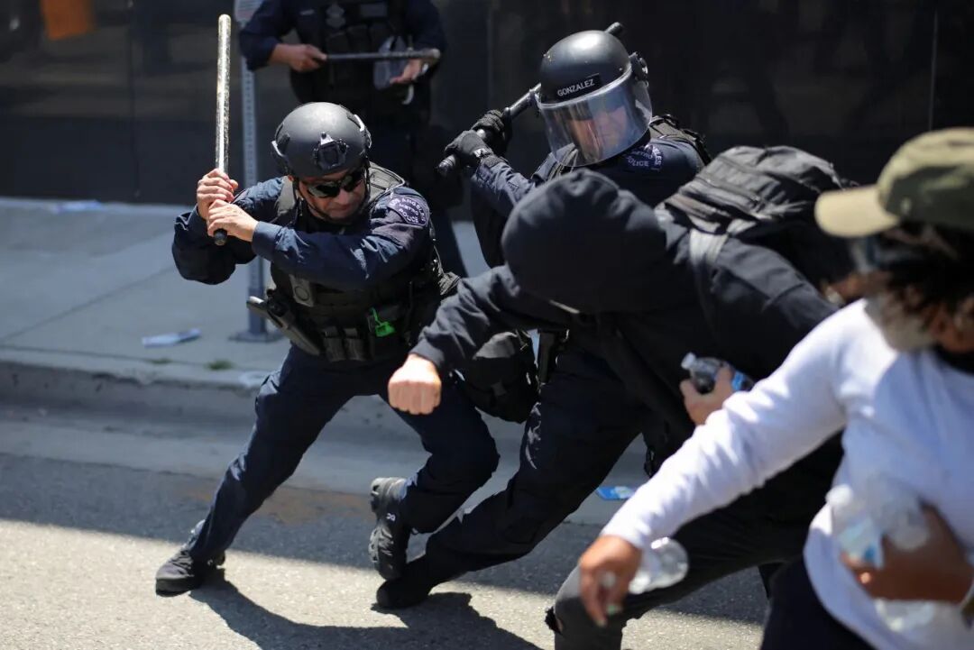 Los Angeles Metro Police officers swing their batons at demonstrators during a protest against federal immigration sweeps in Los Angeles on Sunday.