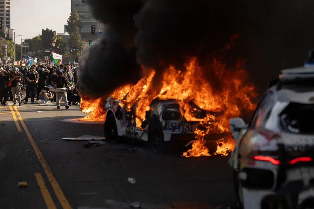 Waymo cars are set on fire as protesters clash with law enforcement near the federal building in Los Angeles, California, on Sunday.