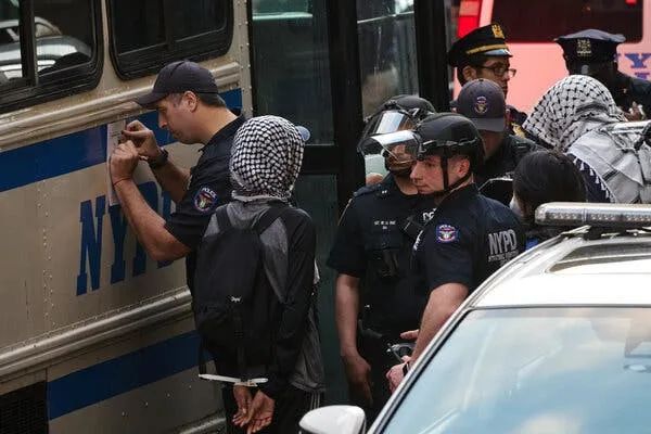 警察聚集在警察局周围，一名示威者被带到一辆公交车上。