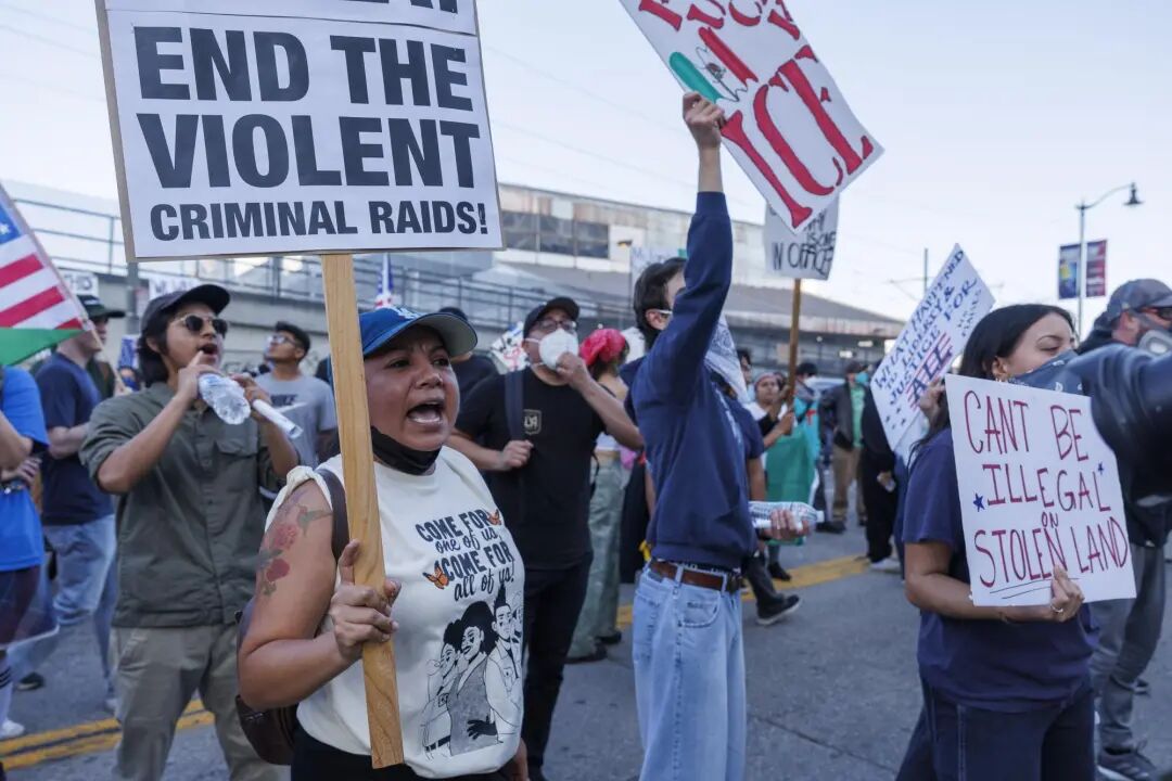 示威者举着抗议移民执法突袭的标语和横幅。