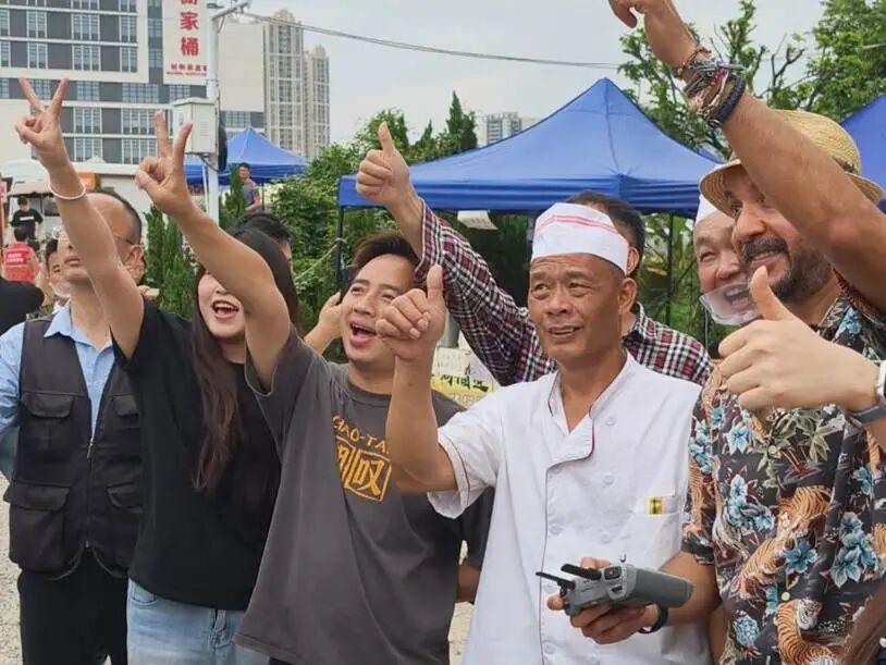 图为莫氏鸡煲小院，莫叔（右三）与海内外游客合影留念。人民网记者 王雅蝶 摄