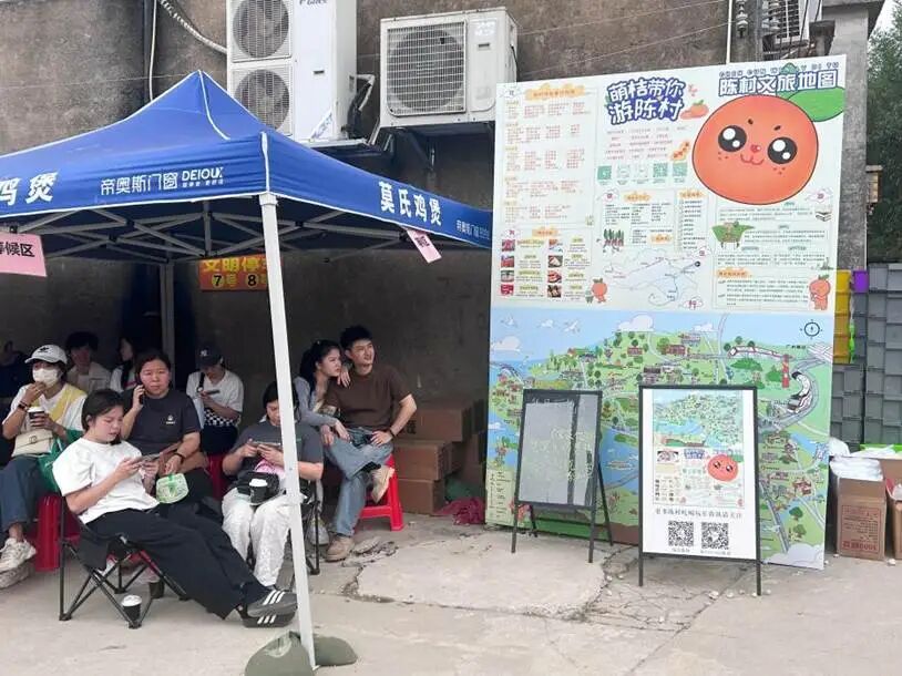 图为莫氏鸡煲“候鸡亭”，游客们在等待之余，了解陈村镇文旅路线。兰航宇 摄