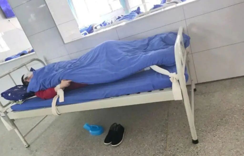 A patient lies strapped to a bed in one of the hospitals. They are usually allowed little contact with their families. Photo: bjnews