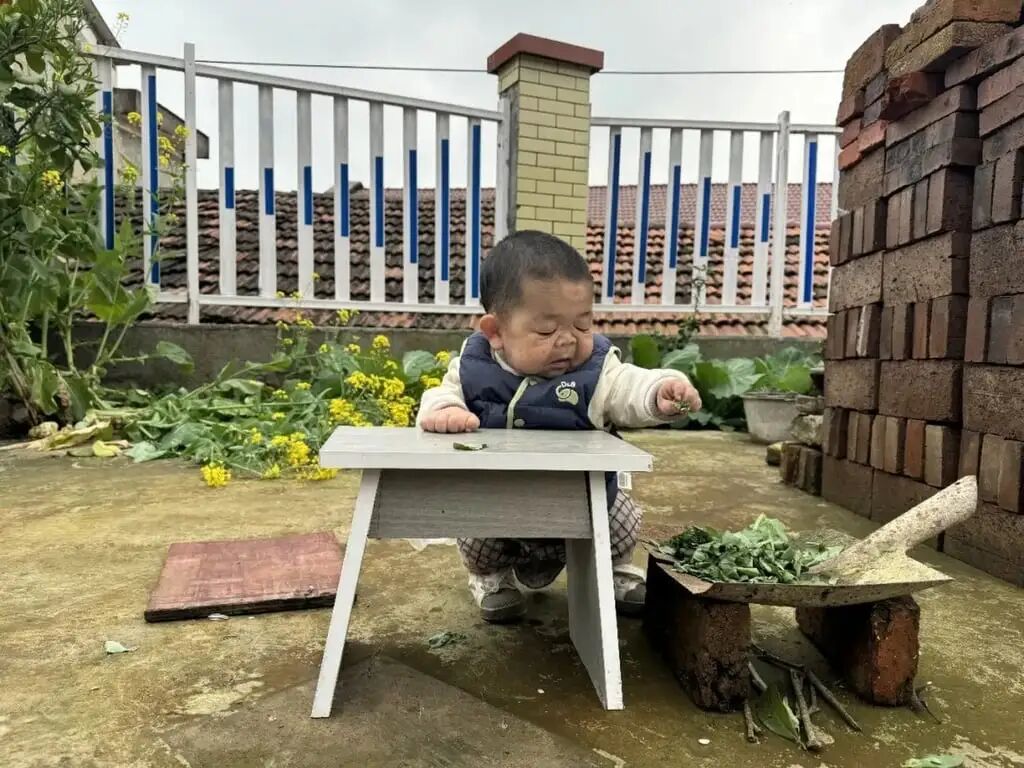 Wang squats at a table while helping out in the family’s garden. Photo: Handout