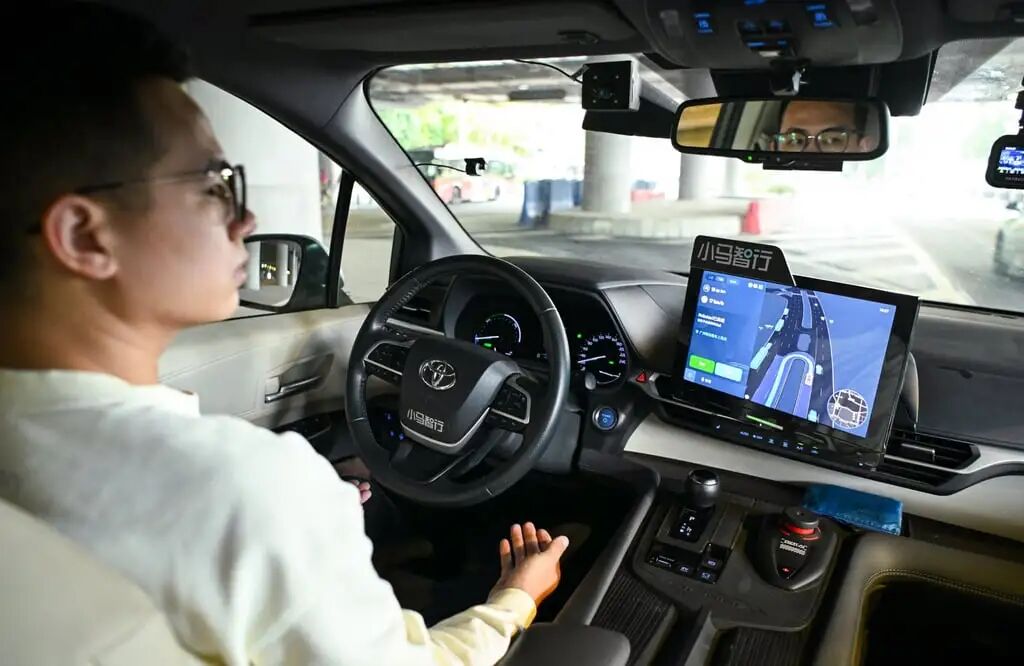 A member of safety staff shows how to drive an autonomous vehicle in southern China. Photo: Xinhua