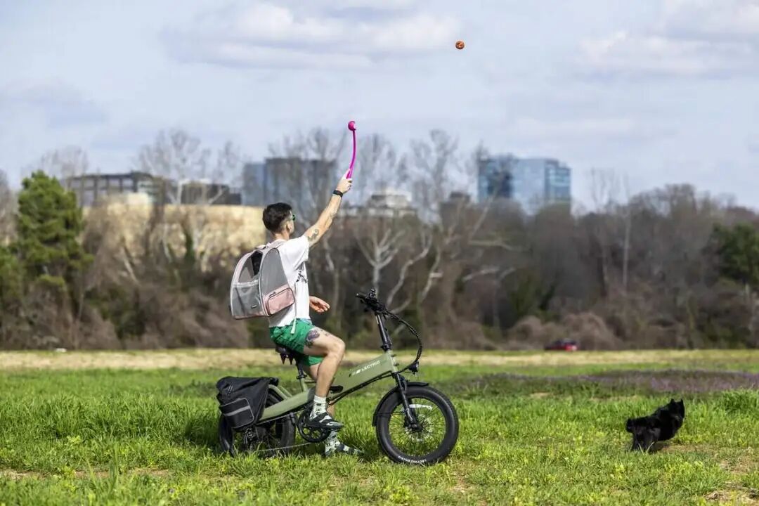 Andrew Gregg plays fetch with his 6-year-old rescue dog, Bubs, while riding his e-bike at Dorothea Dix Park with the Raleigh skyline in the background on Thursday, March 5, 2026.